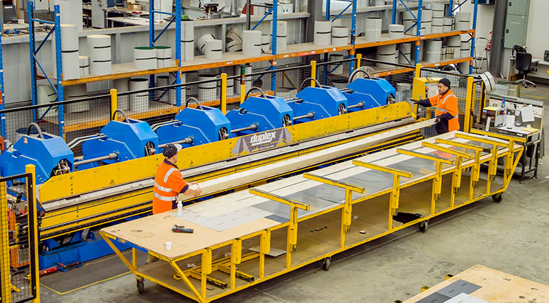 Two employees using machine in factory